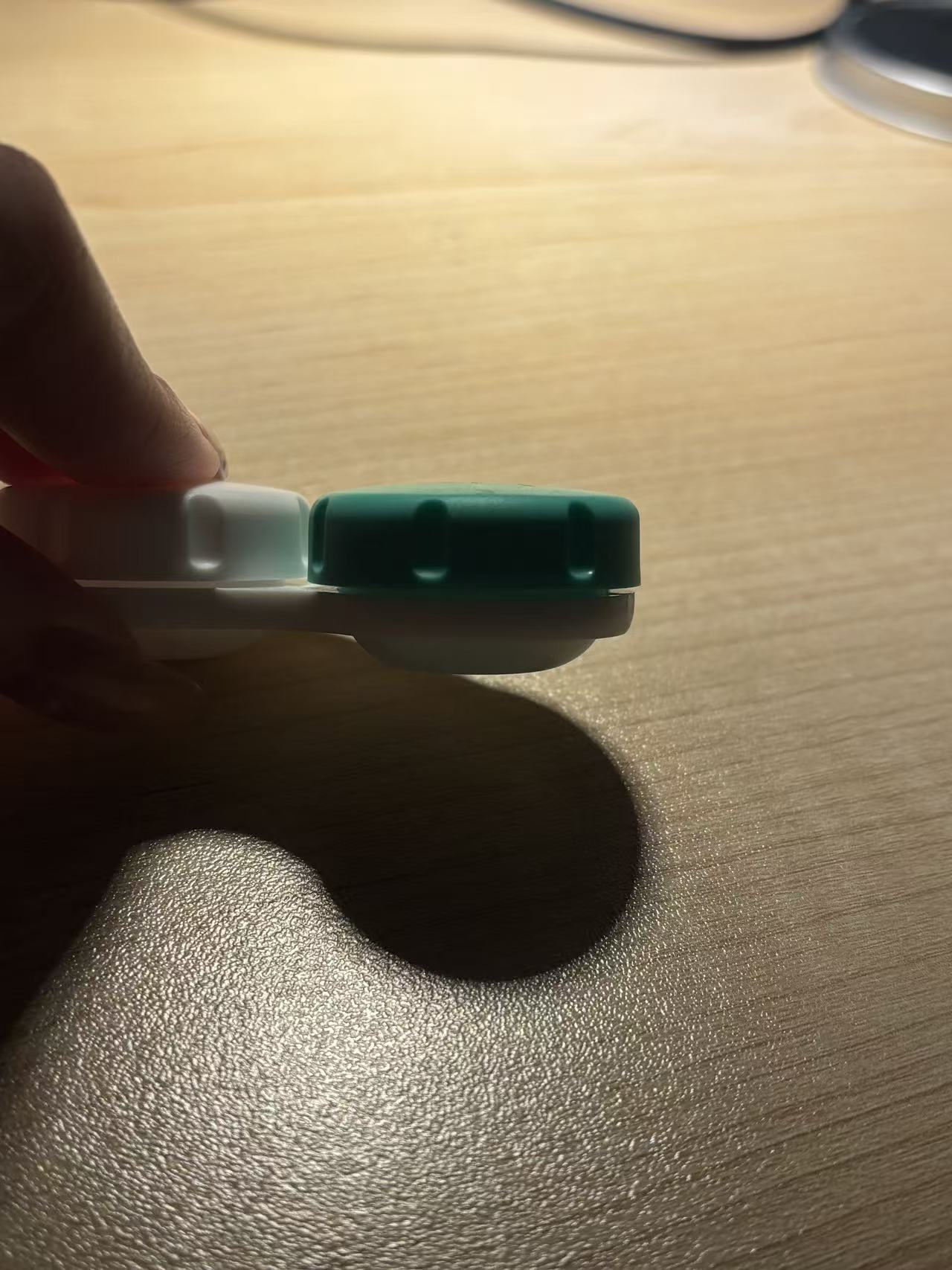 A contact lens case being picked up by fingers.