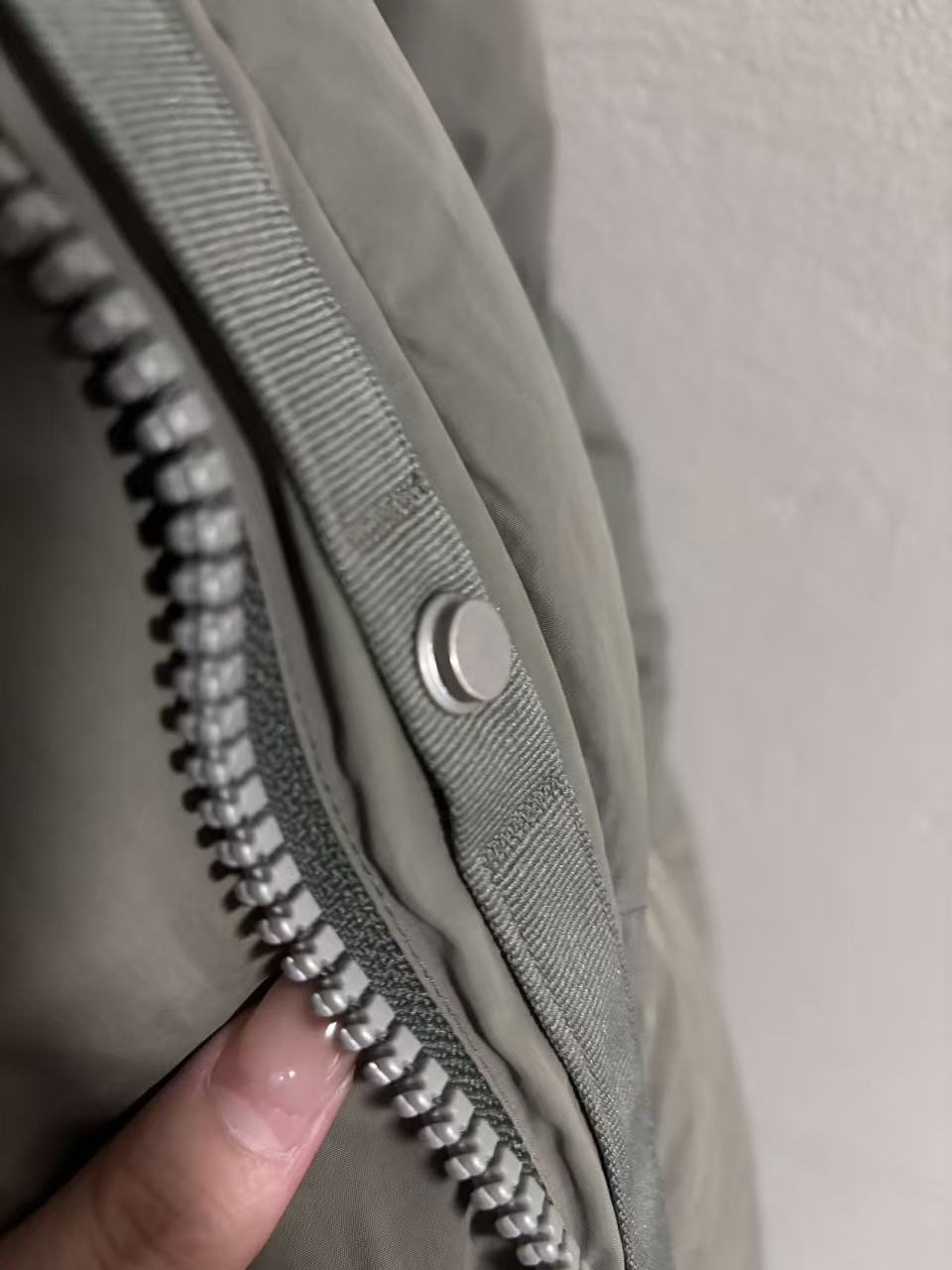 Fingers fastening a snap button on a jacket.