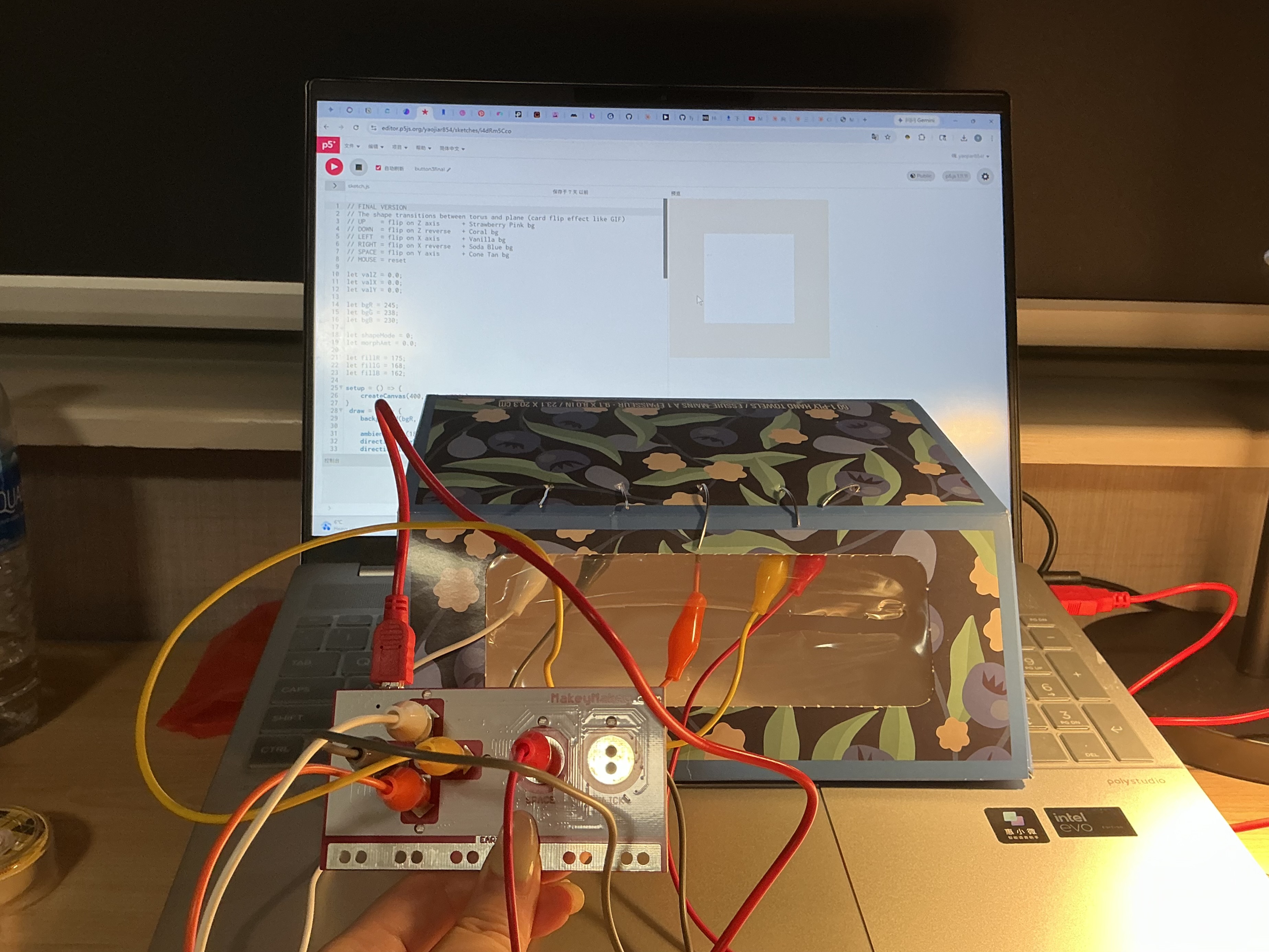 The image displays a laptop showing a blank canvas with the floral box interface placed in front of it, testing the wire loop connections before any interaction begins.