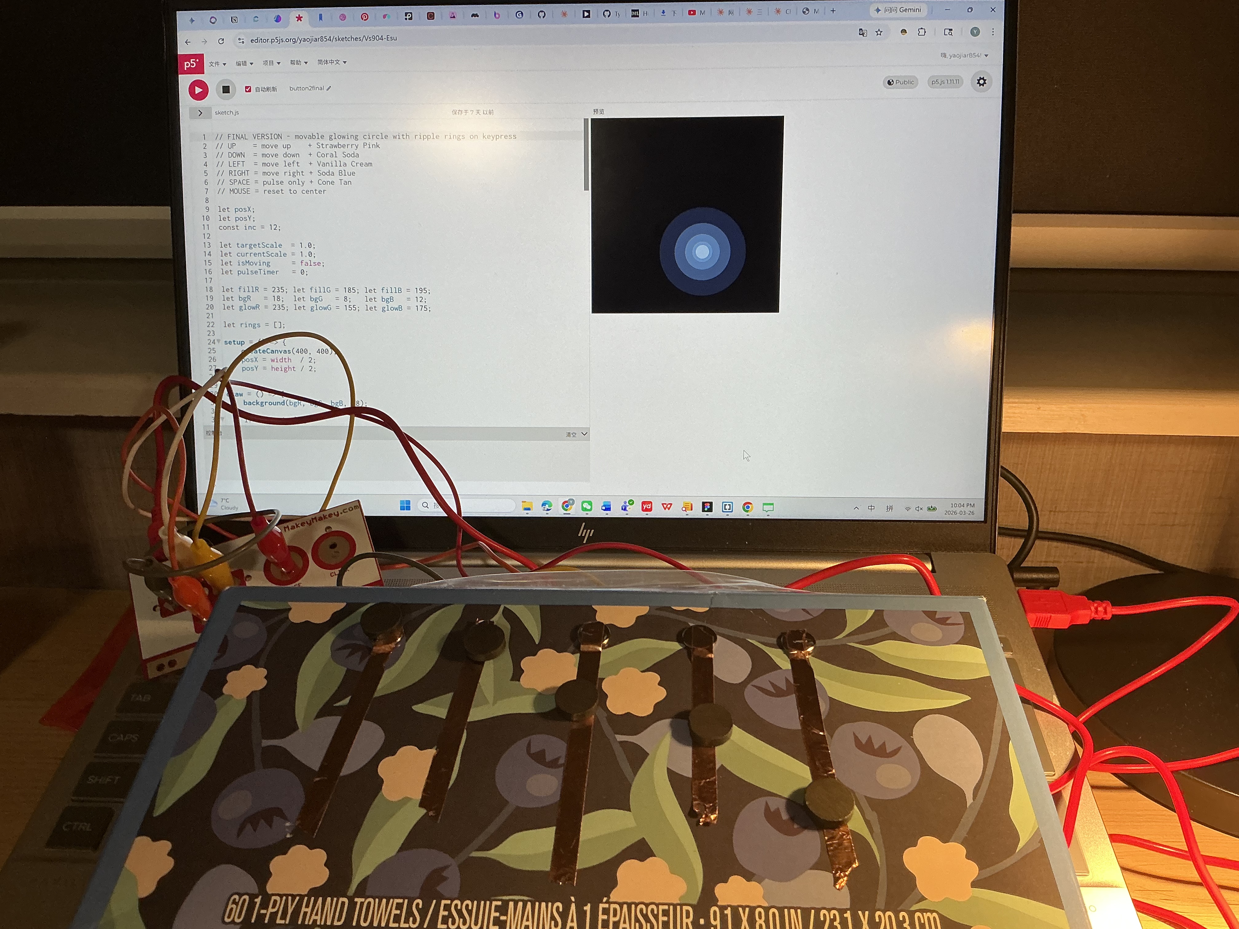 The image displays a laptop showing a dark canvas with a blue glowing circle while the blue floral box with magnet-topped copper tape buttons sits connected below, using copper tape and magnets as the combined input interface.