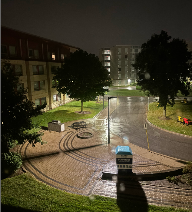 The building in the photo is the exterior of Dormitory Building 1 captured from the third floor interior during a rainy night.