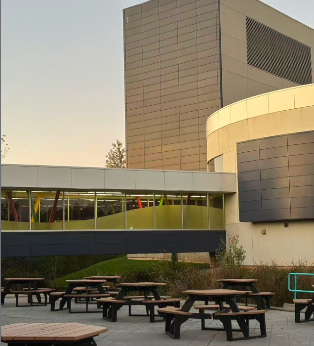 The photo shows an exterior view of the connection point between the school's J Building and the glass corridor.