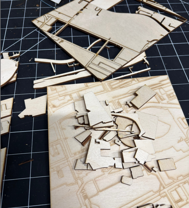 The image shows laser-cut wooden map fragments, which are components of the map.